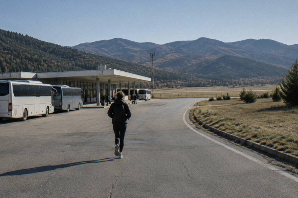 An open road winding through green Rhodope mountain hillsides on a clear day