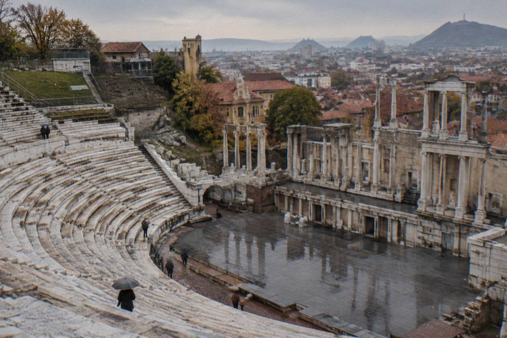 Marble rows of an ancient Roman theatre overlooking a modern city skyline