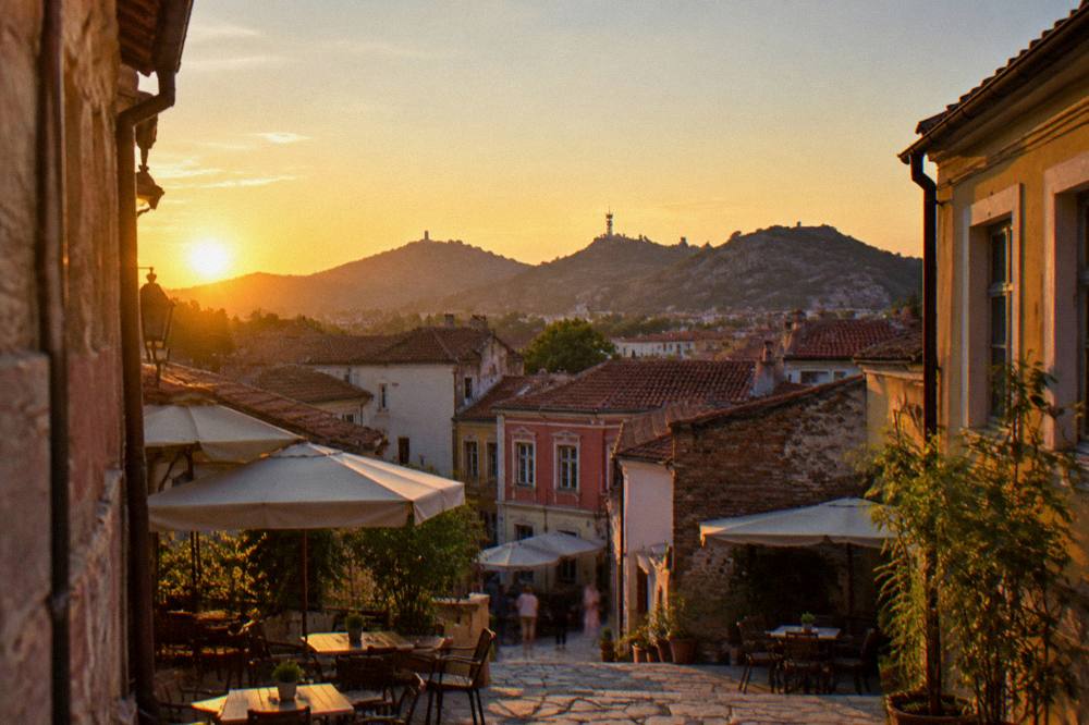 View across Kapana rooftops toward the hills of Plovdiv at golden hour