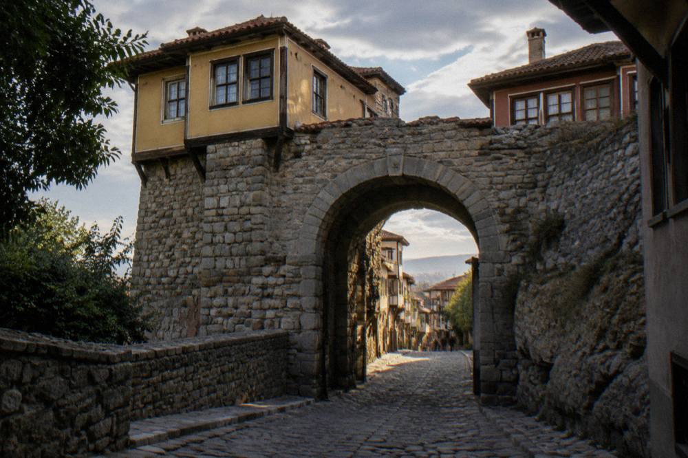 Stone gate of Hisar Kapia with old houses above it in the evening