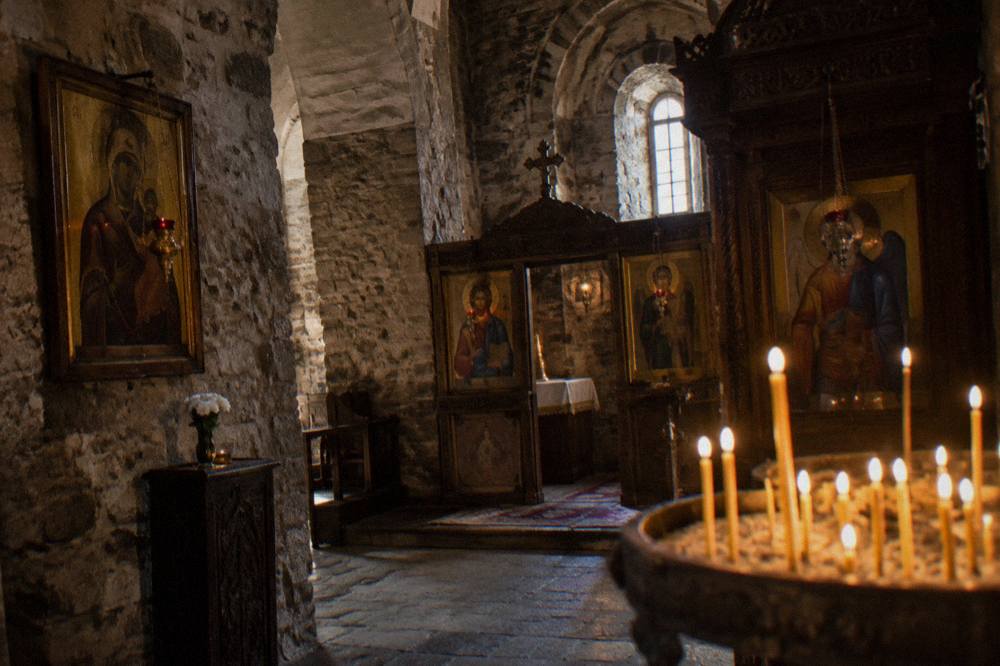 Candle-lit interior of an Armenian church with ornate icons and stone walls