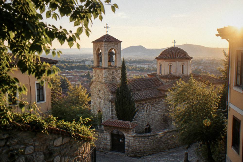 Bell tower and dome of a city church seen from a leafy Plovdiv side street