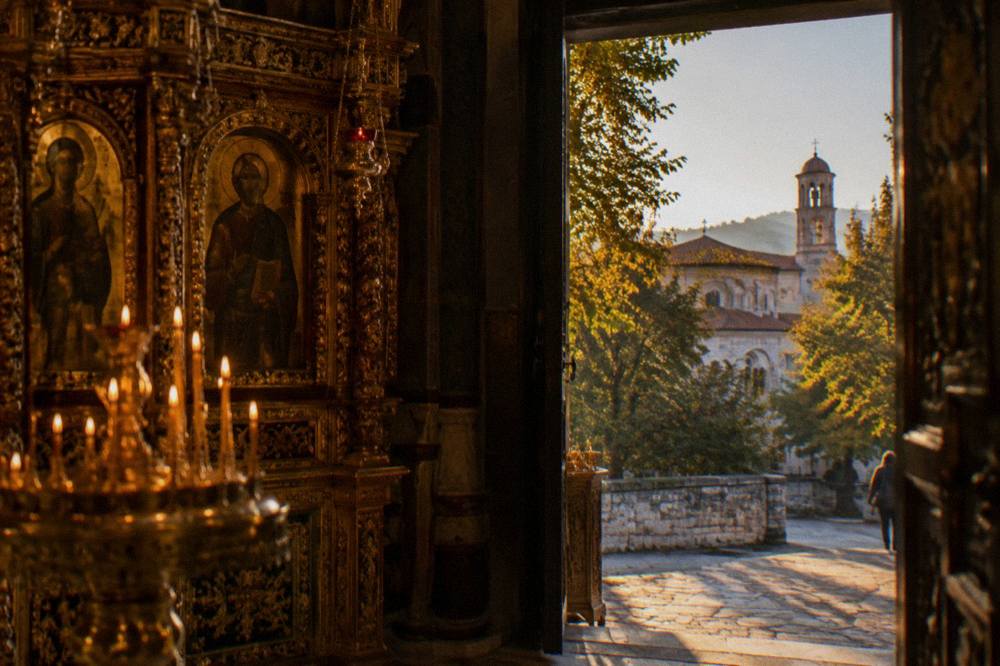 Ornate Orthodox interior with gilded iconostasis and rows of candles