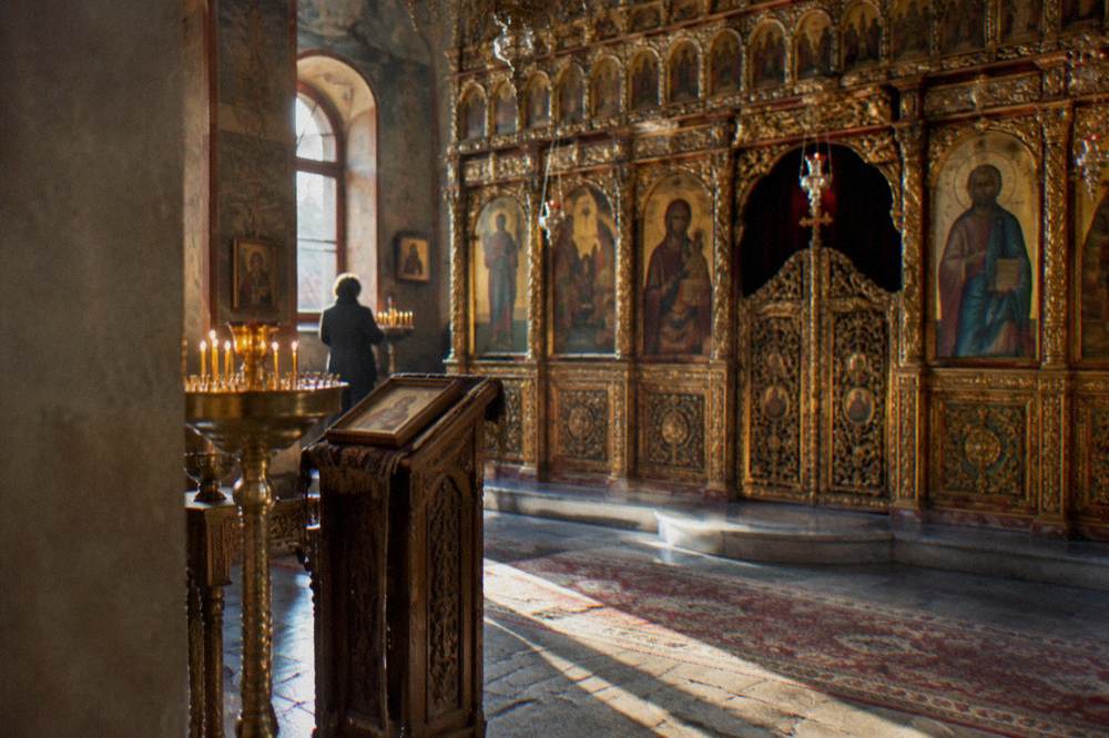 A gilded iconostasis with rows of icons inside a small Orthodox church