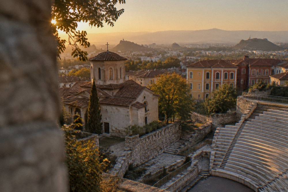 A stone amphitheatre with rows of marble seats overlooking a city skyline