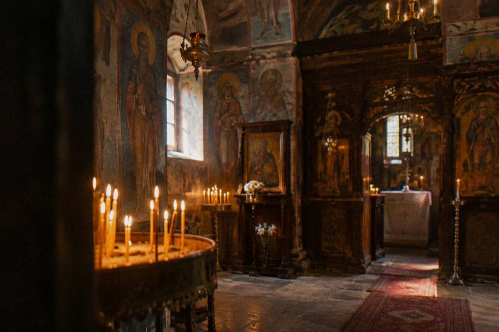A church interior lit by candlelight with painted walls and hanging lamps