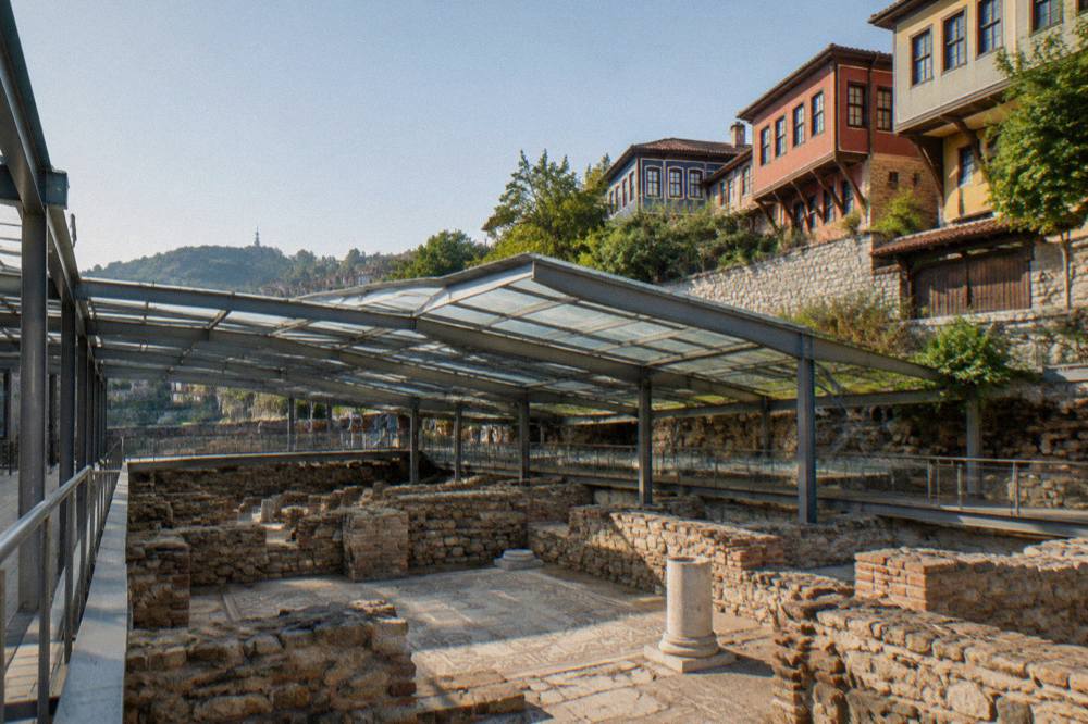 Wide view of the excavated basilica foundations under a modern protective structure in central Plovdiv