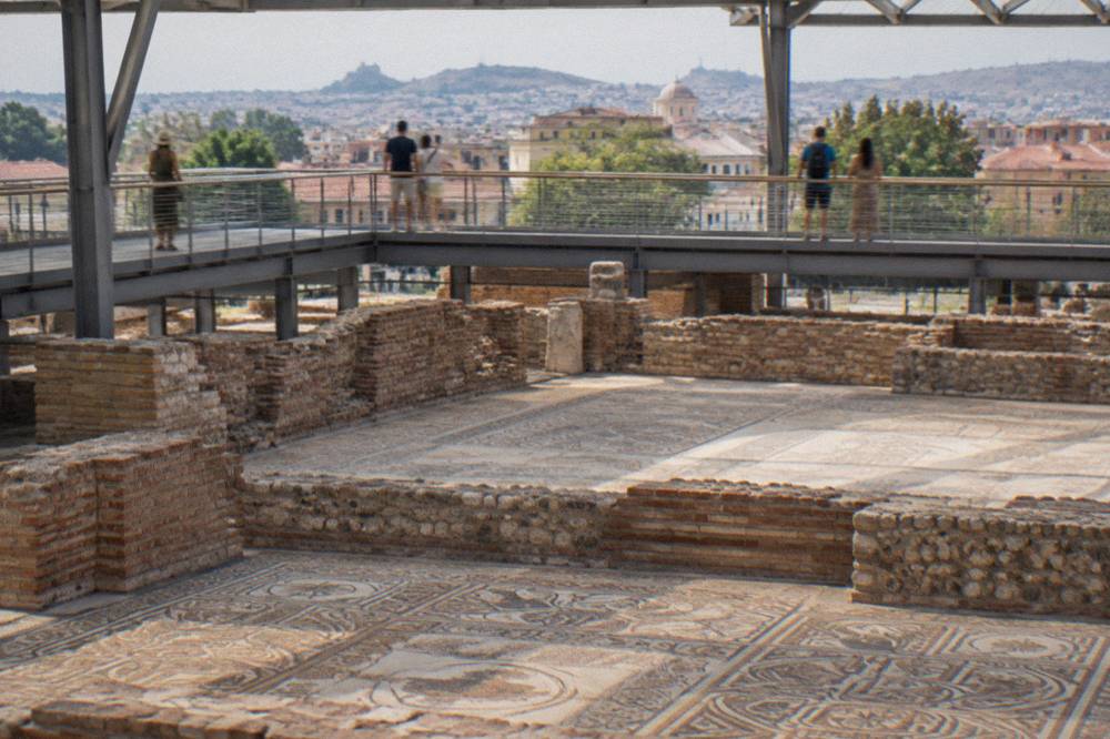 Visitors on a raised walkway viewing ancient mosaic carpets inside the Bishop's Basilica in Plovdiv
