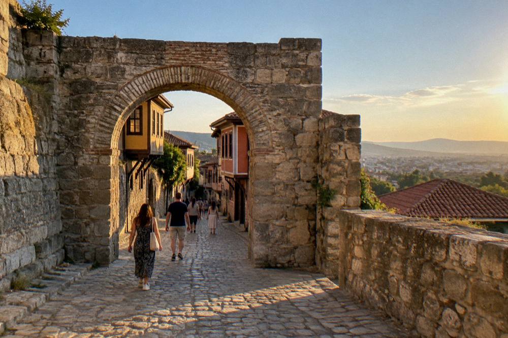 Visitors walking through the stone gate of Hisar Kapia into Plovdiv's Old Town at golden hour