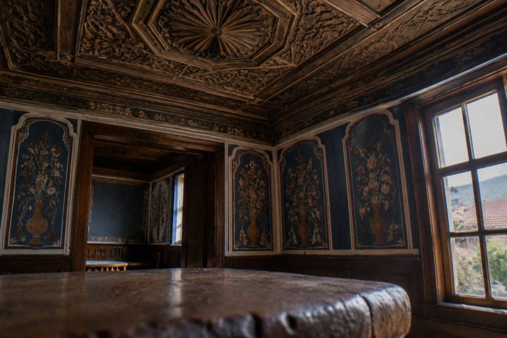 An ornately carved wooden ceiling and painted wall inside a Bulgarian revival house museum