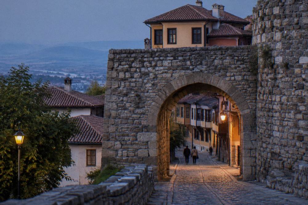 A stone gate arch of Hisar Kapia in Plovdiv with old houses rising behind it