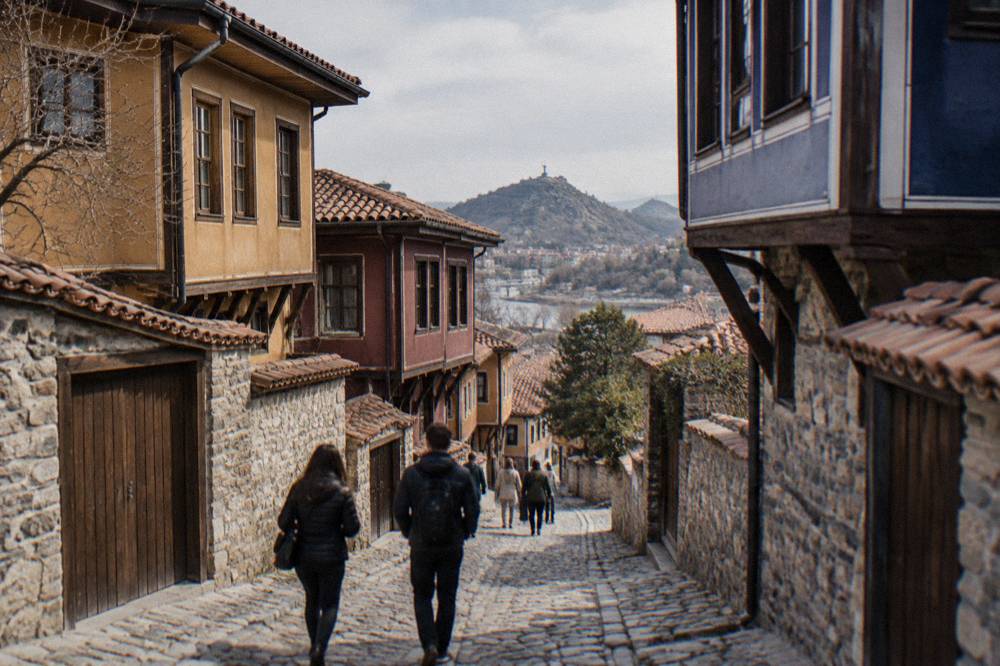 Visitors walking on a stone street between old houses in Plovdiv Old Town on a bright afternoon