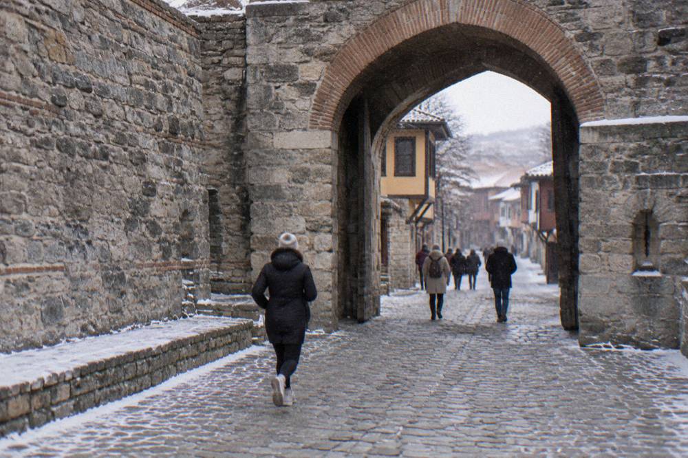 Visitors walking through the stone arch of Hisar Kapia in Plovdiv