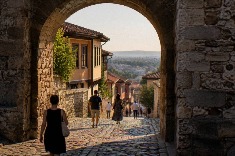 The Hisar Kapia arch in warm evening light with people passing through