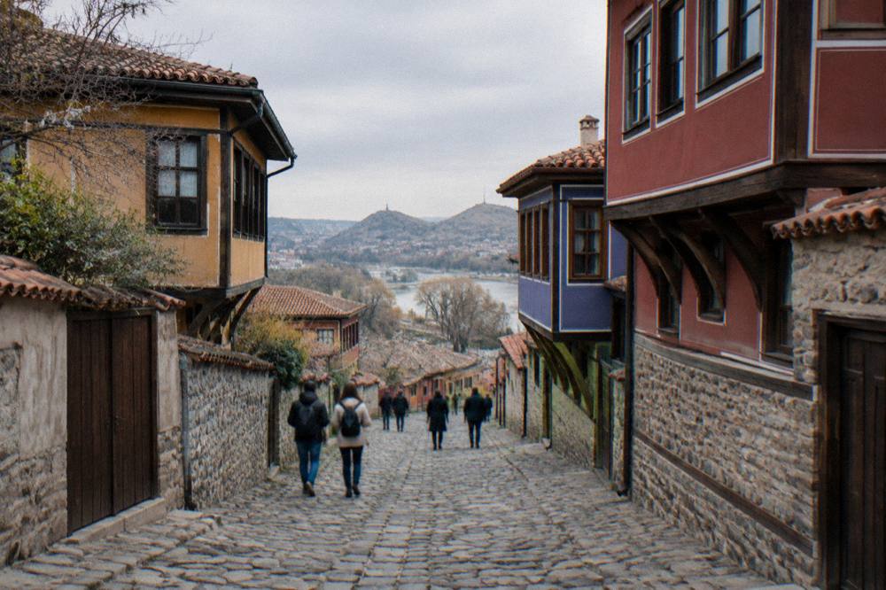 Visitors walking along a stone-paved Old Town street between revival houses in Plovdiv