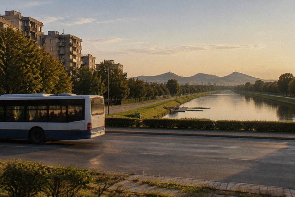 A city bus passing blocks of flats on a wide boulevard on the way to the canal area