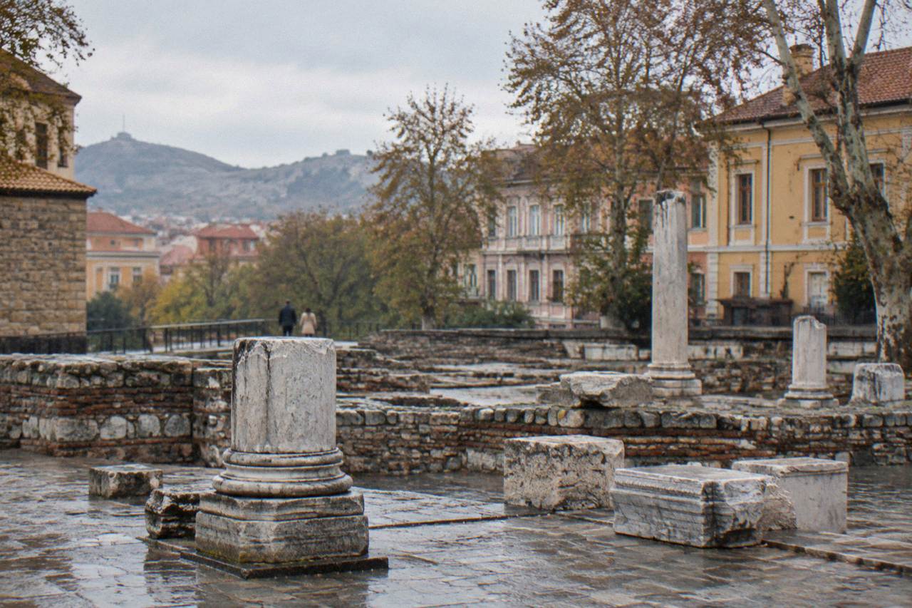 Stone foundations and carved marble blocks of an ancient Roman public square under an open sky