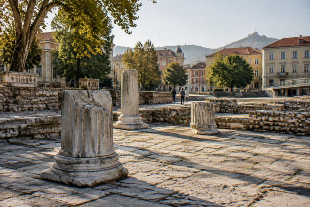 Sunlit ancient stone pavement with modern city buildings visible in the background
