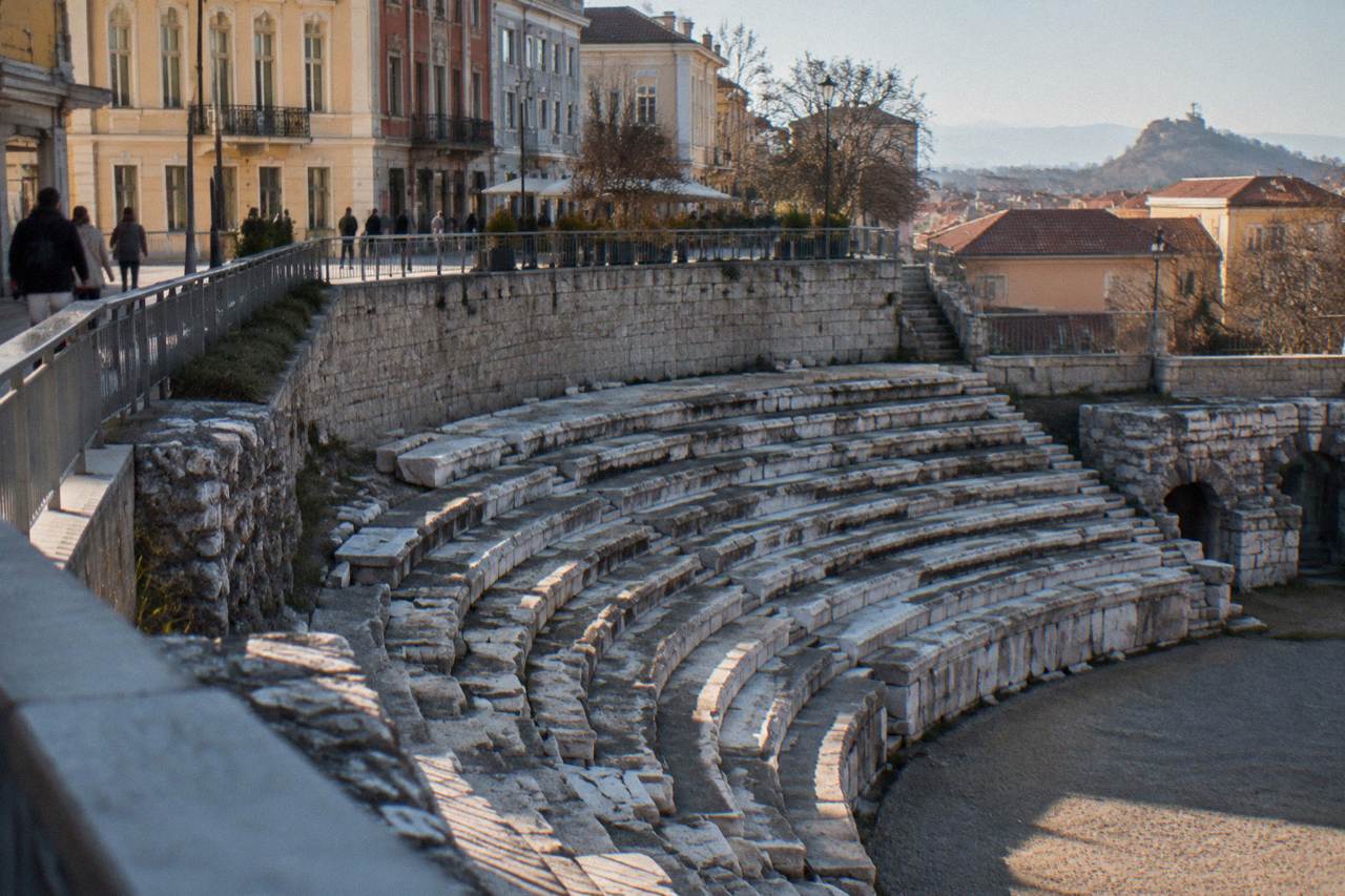 The curved stone seating of the Roman Stadium sphendone in Plovdiv below modern square walls
