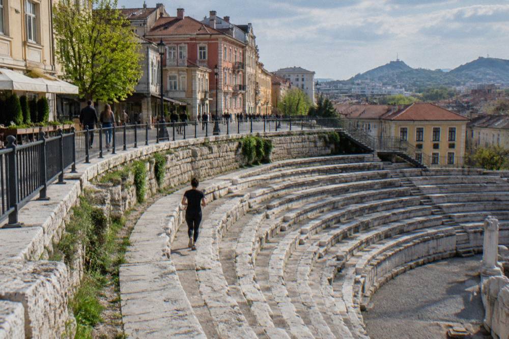 Thirteen stepped rows of ancient stone seats curving below street level in the Plovdiv stadium sphendone