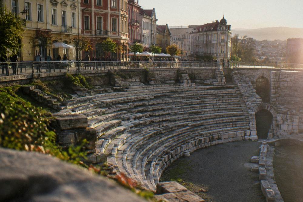 Curved stone tiers of a Roman stadium sphendone beneath a pedestrian street