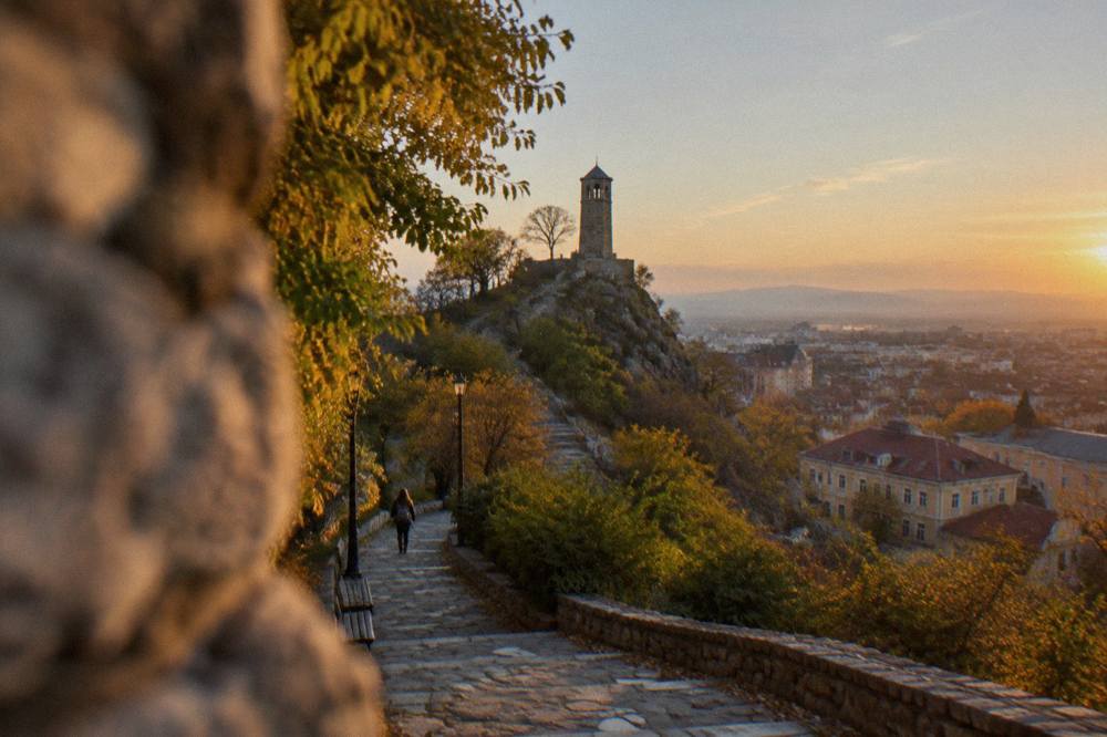 A paved path climbing a small city park toward a clock tower in Plovdiv