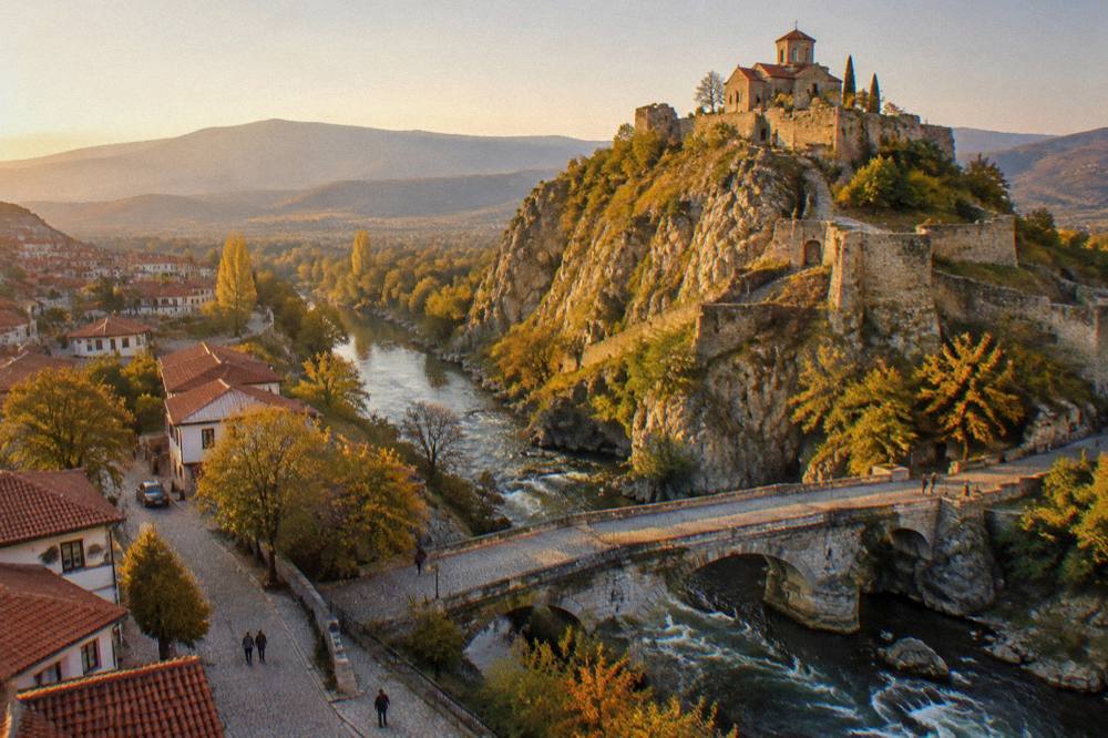 A small town street with a stone bridge over a fast mountain river