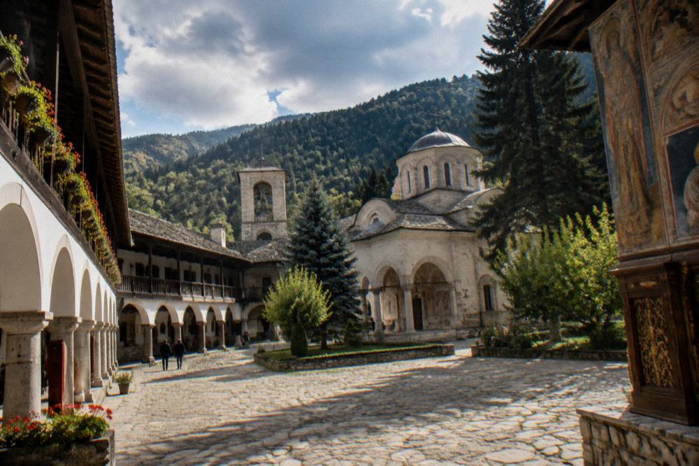 Frescoed walls and an ornate iconostasis inside an Orthodox monastery church