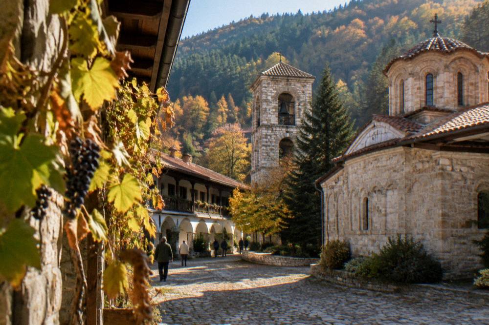 Autumn trees in a mountain valley with a monastery roof visible among the foliage