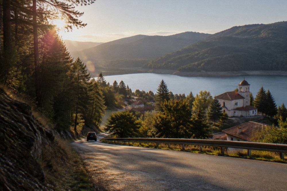 A mountain road winding through pine forest toward a Rhodope town