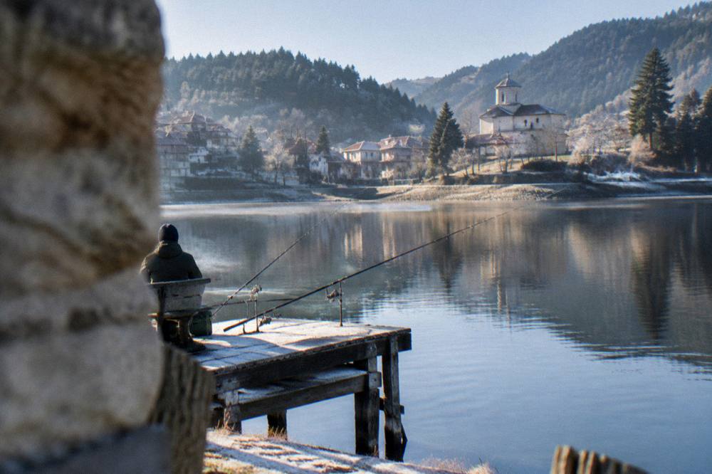 Fishing rods on a wooden jetty above still reservoir water in morning light