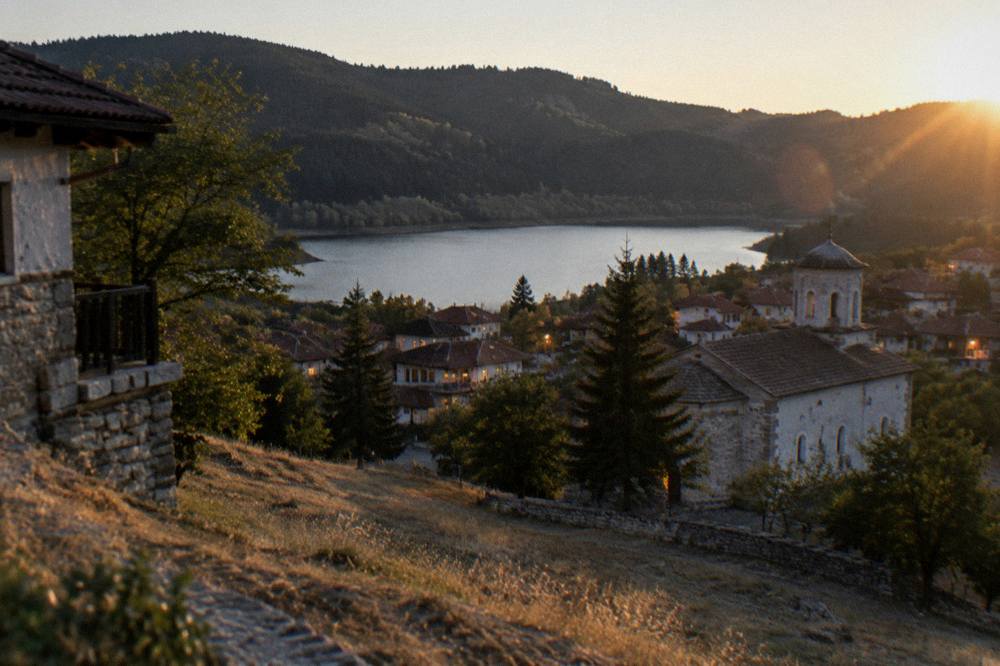 An evening view across a small town with lit windows and dark forest beyond