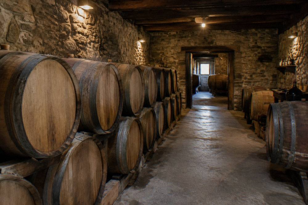 A wine cellar with oak barrels stacked along stone walls in a Bulgarian village winery