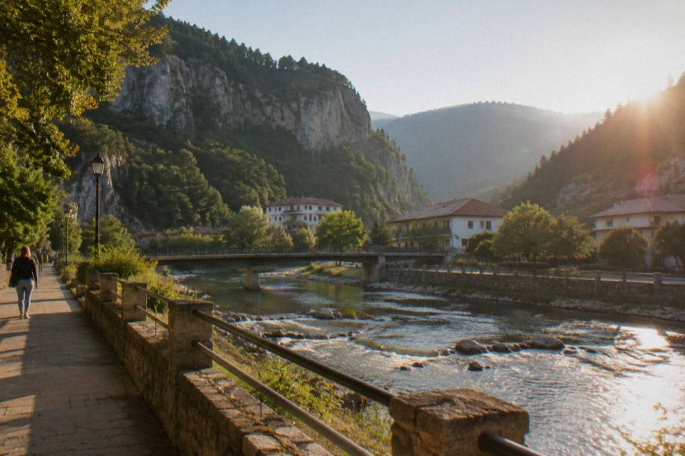 Tall limestone cliffs rising above a narrow forested gorge with a river below