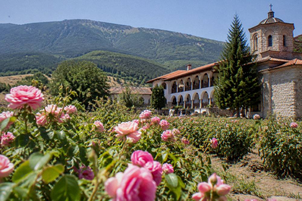 A mountain monastery complex with arcaded walkways below forested slopes