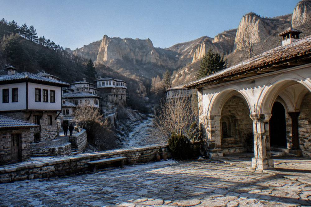 A stone monastery courtyard with arched porticoes under a tiled roof