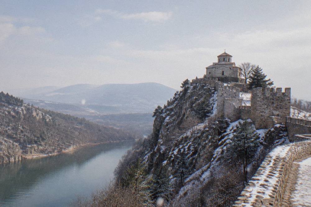 Stone walls of Asen's Fortress on a cliff above a forested river valley