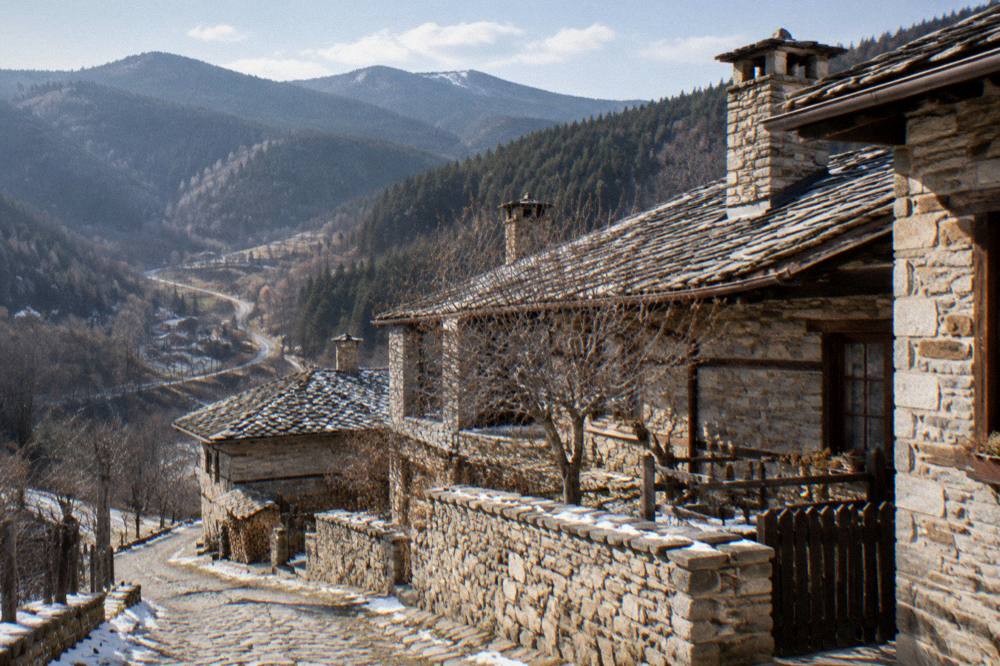 A stone village street with slate-roofed houses on a Rhodope hillside