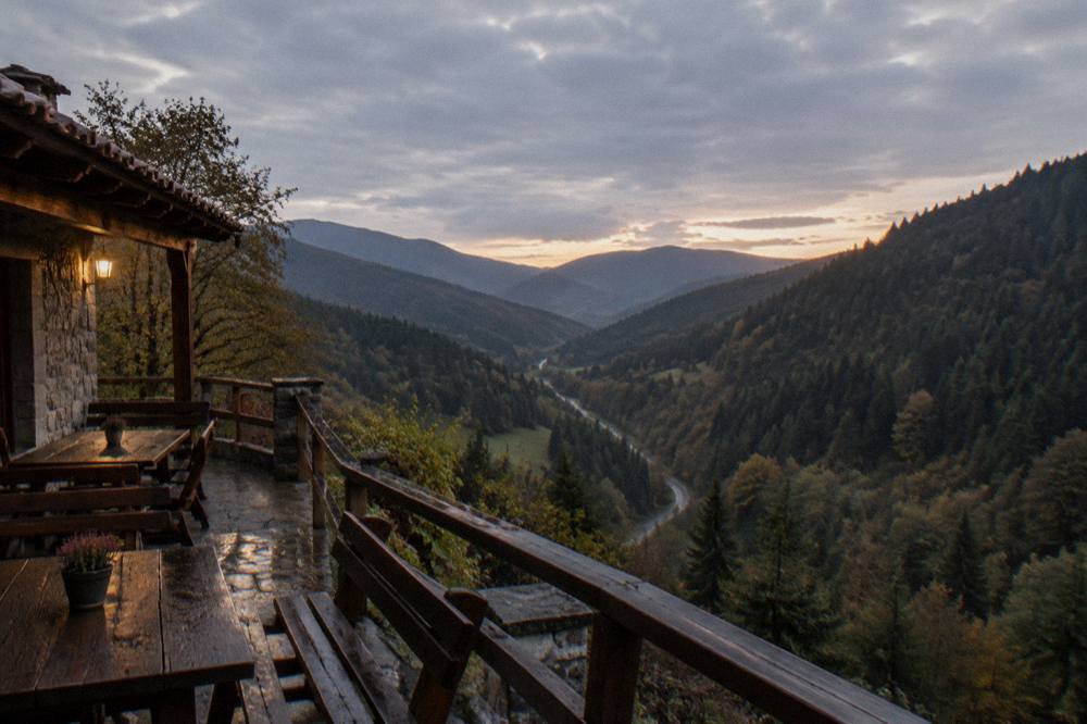 A small guesthouse terrace overlooking a forested valley at dusk