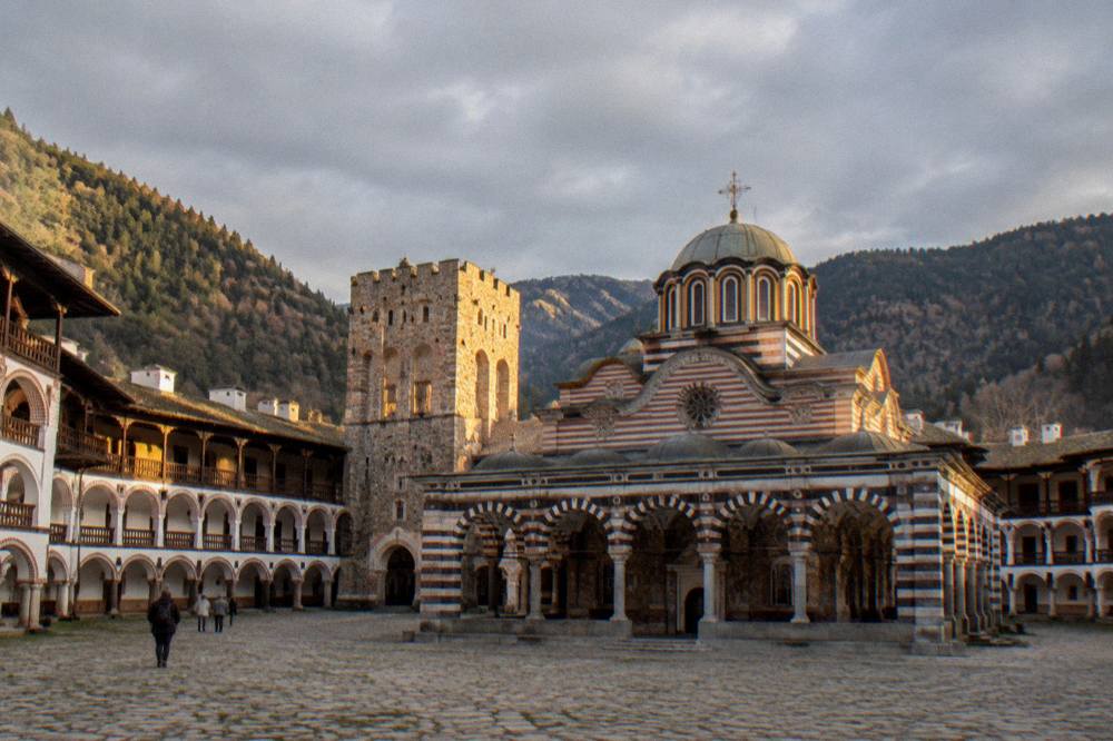 Monastery walls and tower at dusk with warm light on the stone facade