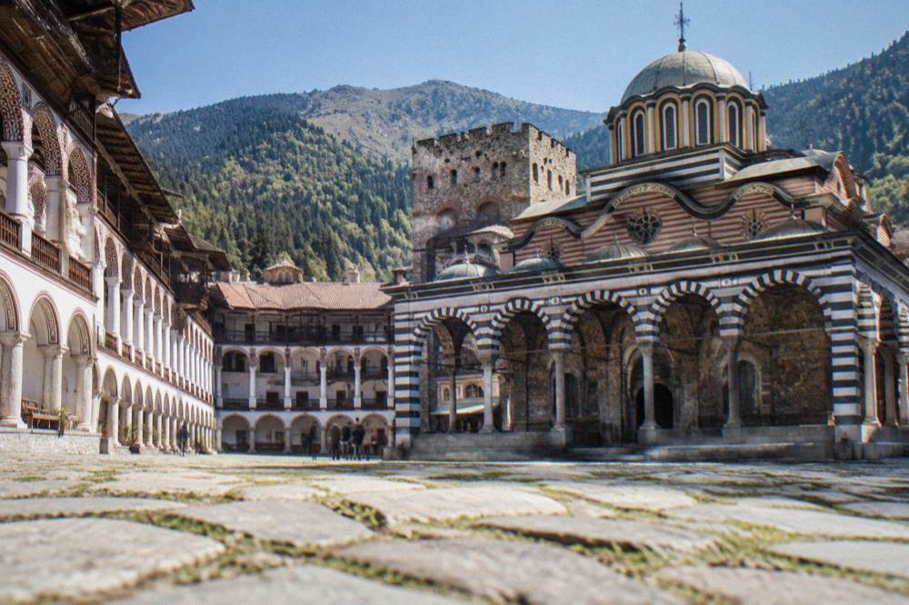 Striped arcaded monastery courtyard in a forested mountain valley