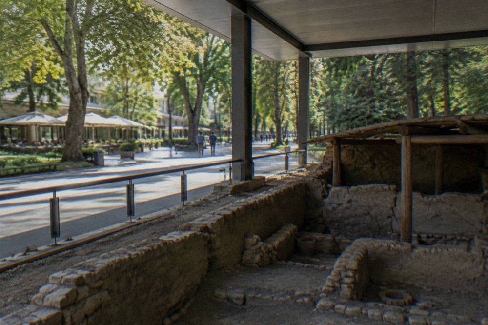 An excavated prehistoric dwelling with clay walls under a modern museum roof