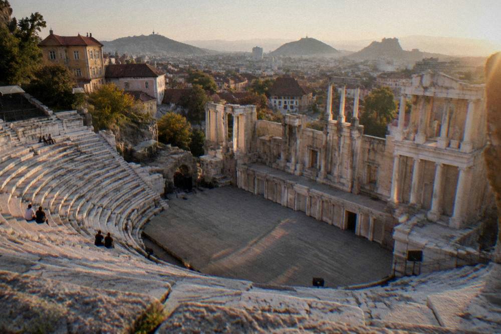 Marble rows of an ancient theatre framed by a modern city skyline
