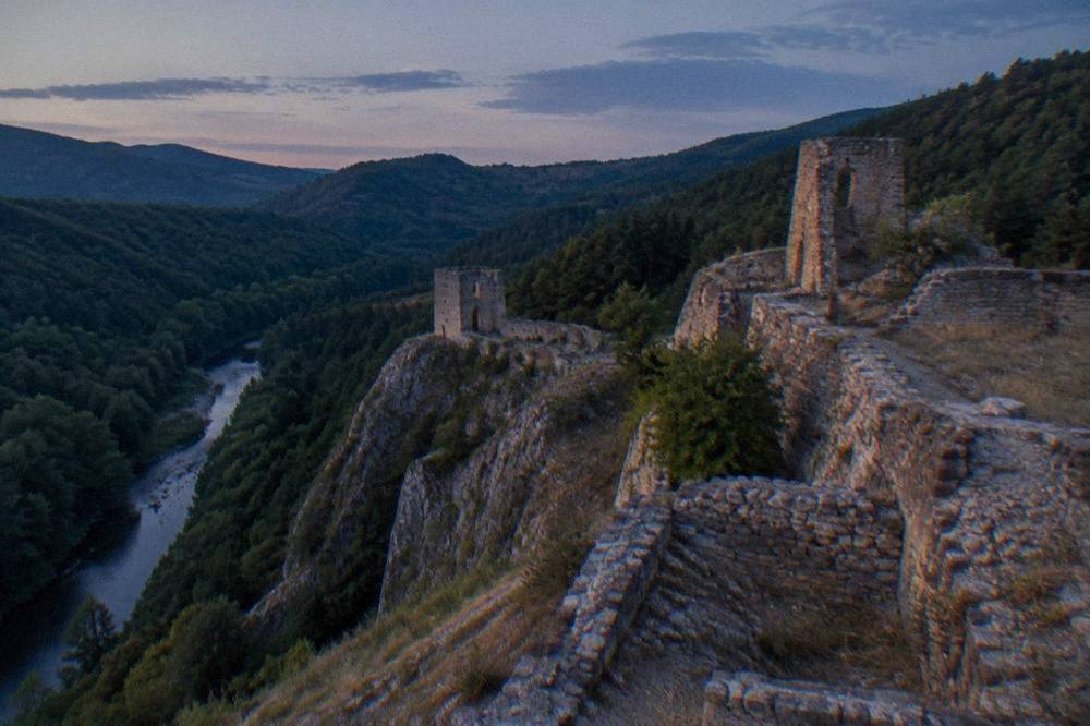 Foundation walls of an old fortress following the crest of a wooded hill