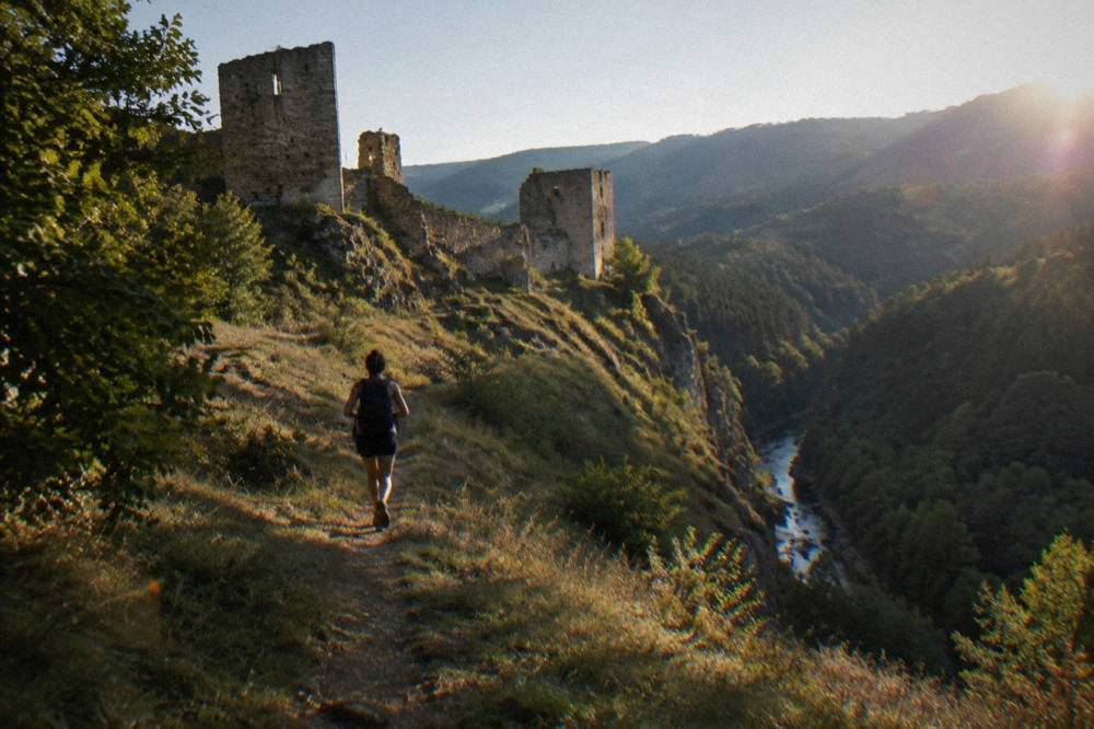 A forest footpath climbing toward a grassy ridge with distant valley views