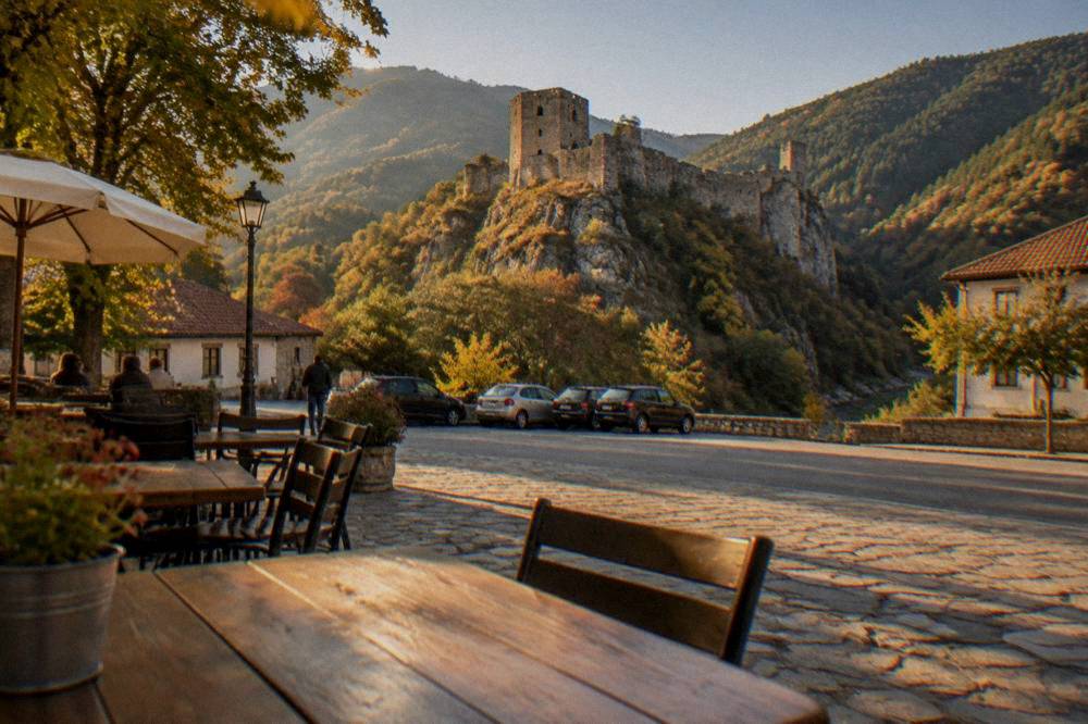 A simple Bulgarian town square with cafe tables and parked cars