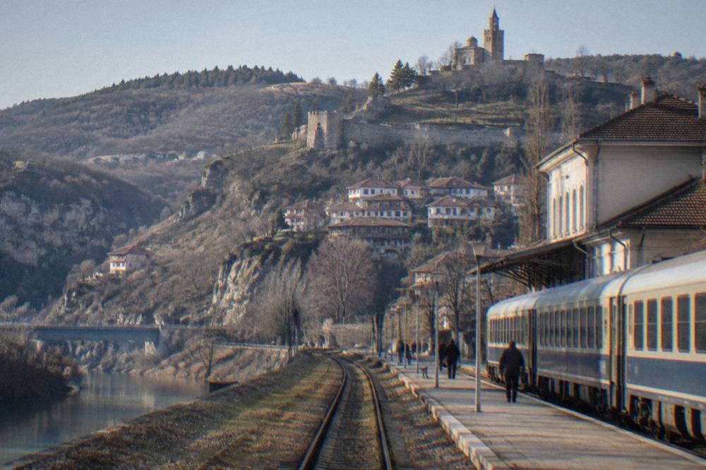A Bulgarian railway platform with a passenger train waiting beside a station building