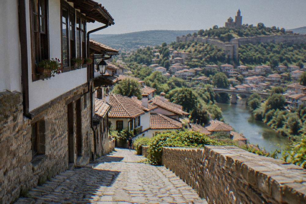 Steep cobbled lanes with old houses rising above a river in a Bulgarian town