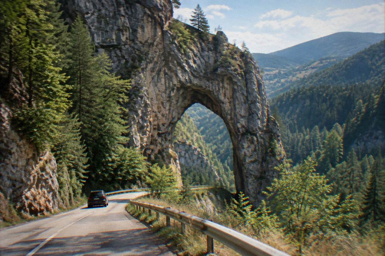 A tall natural marble arch in a green forested gorge in the Rhodope Mountains