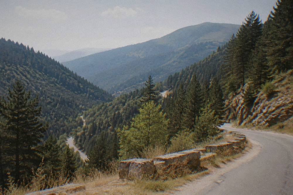 A winding mountain road through pine forests in the Rhodope Mountains